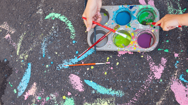 Muffin tin with paint and chalk paint designs on pavement
