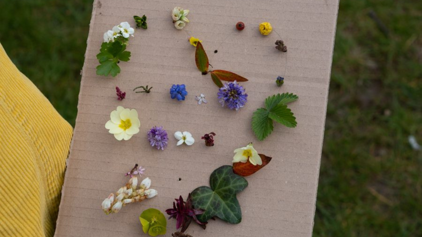 Cardboard with holes punched with wildflowers sticking through in the shape of a heart. Image from Thimbleandtwig.com