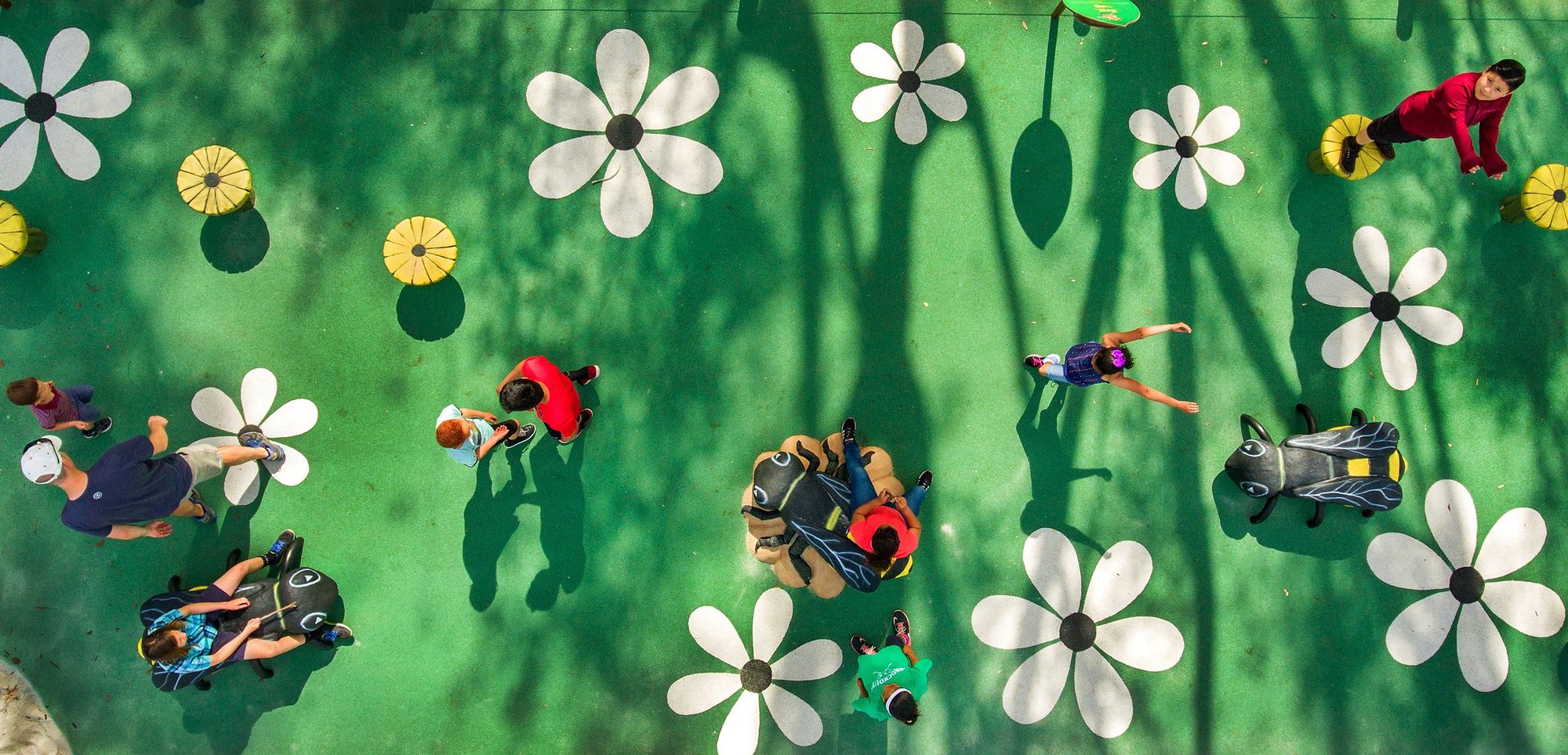 Top View of Bee Themed Park with flowers and children playing on life-size bees.