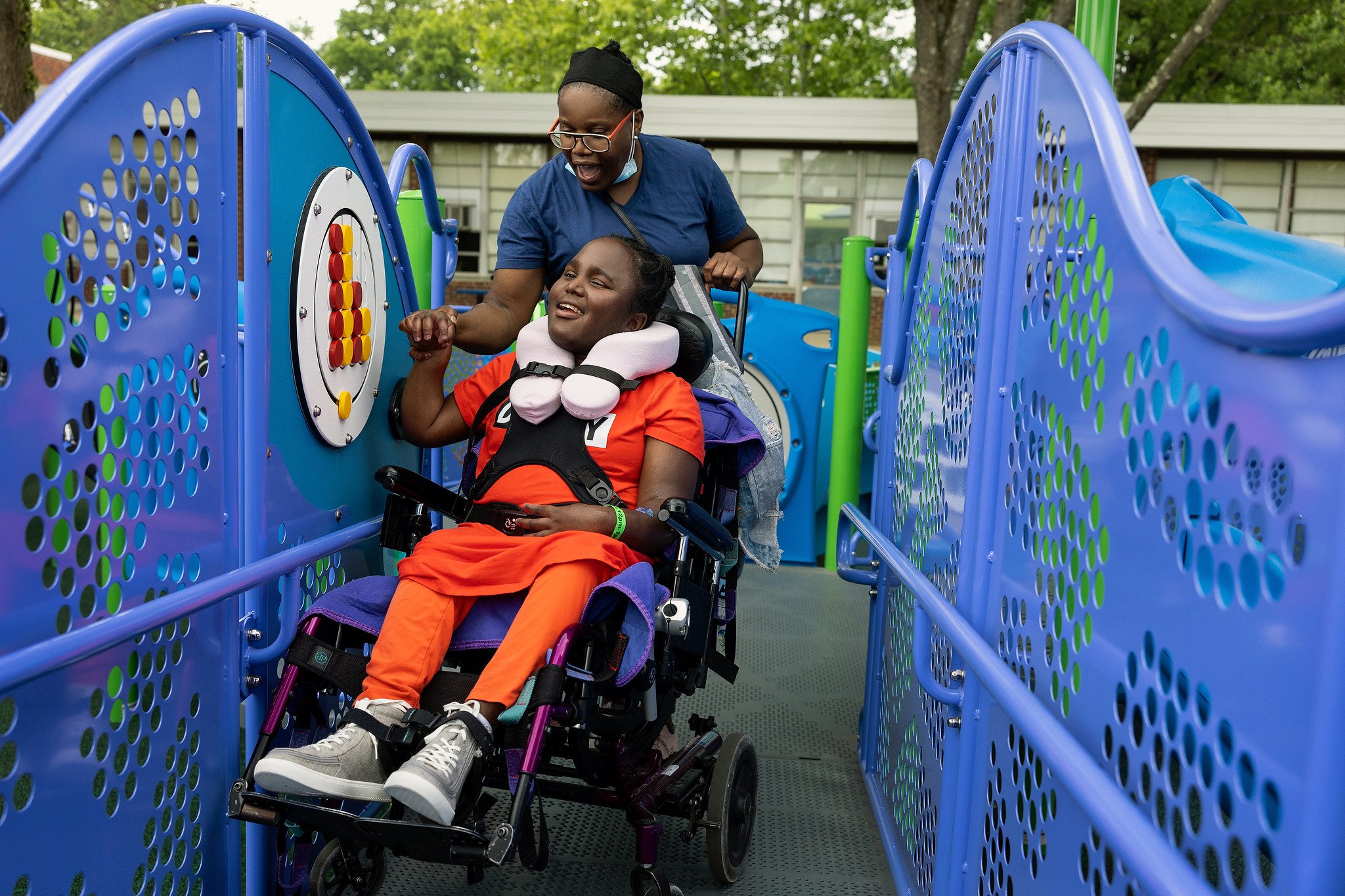 Child in wheelchair with mother guiding hands to use sensory play equipment