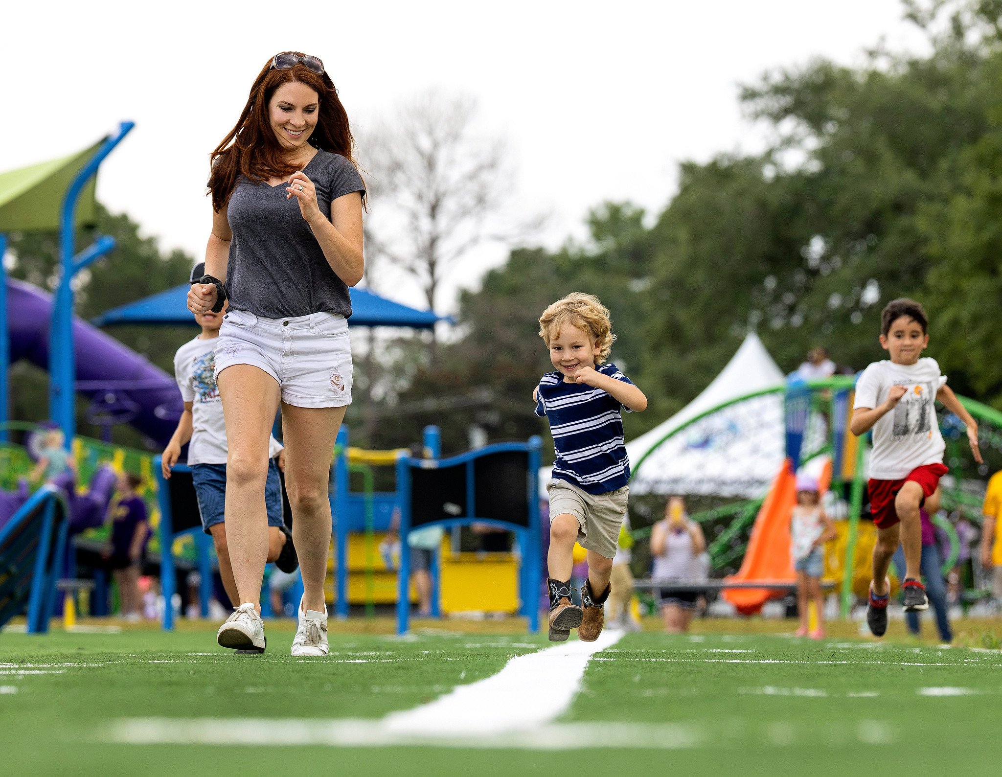 Mother and son running on turf at Playcore Park