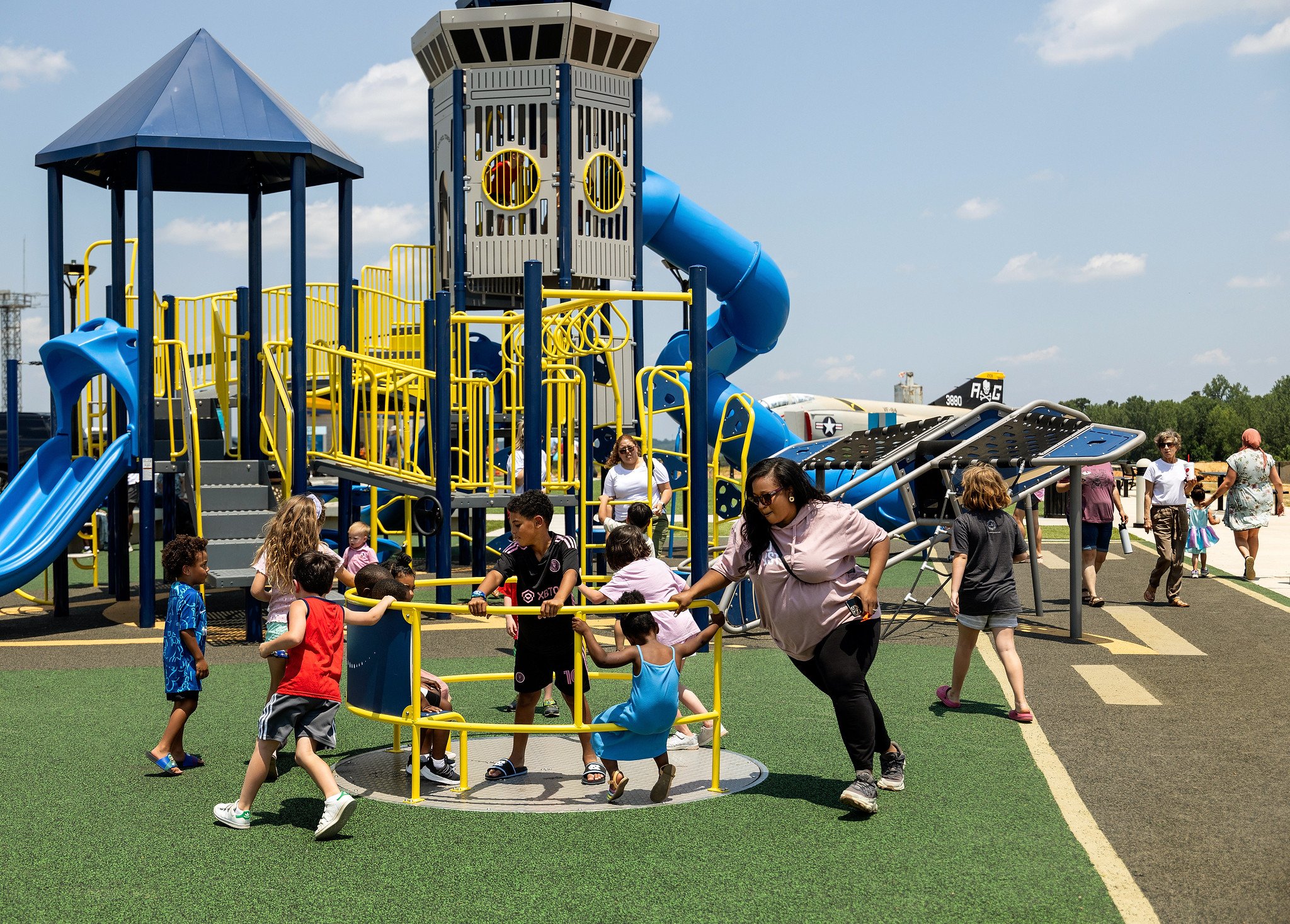 Mom pushing kids on inclusive whirl merry-go-round