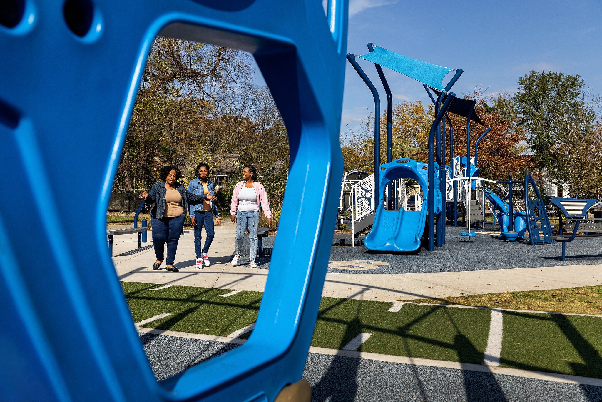 Women enjoying walk on paved trail surrounding IMPACT Parks playground