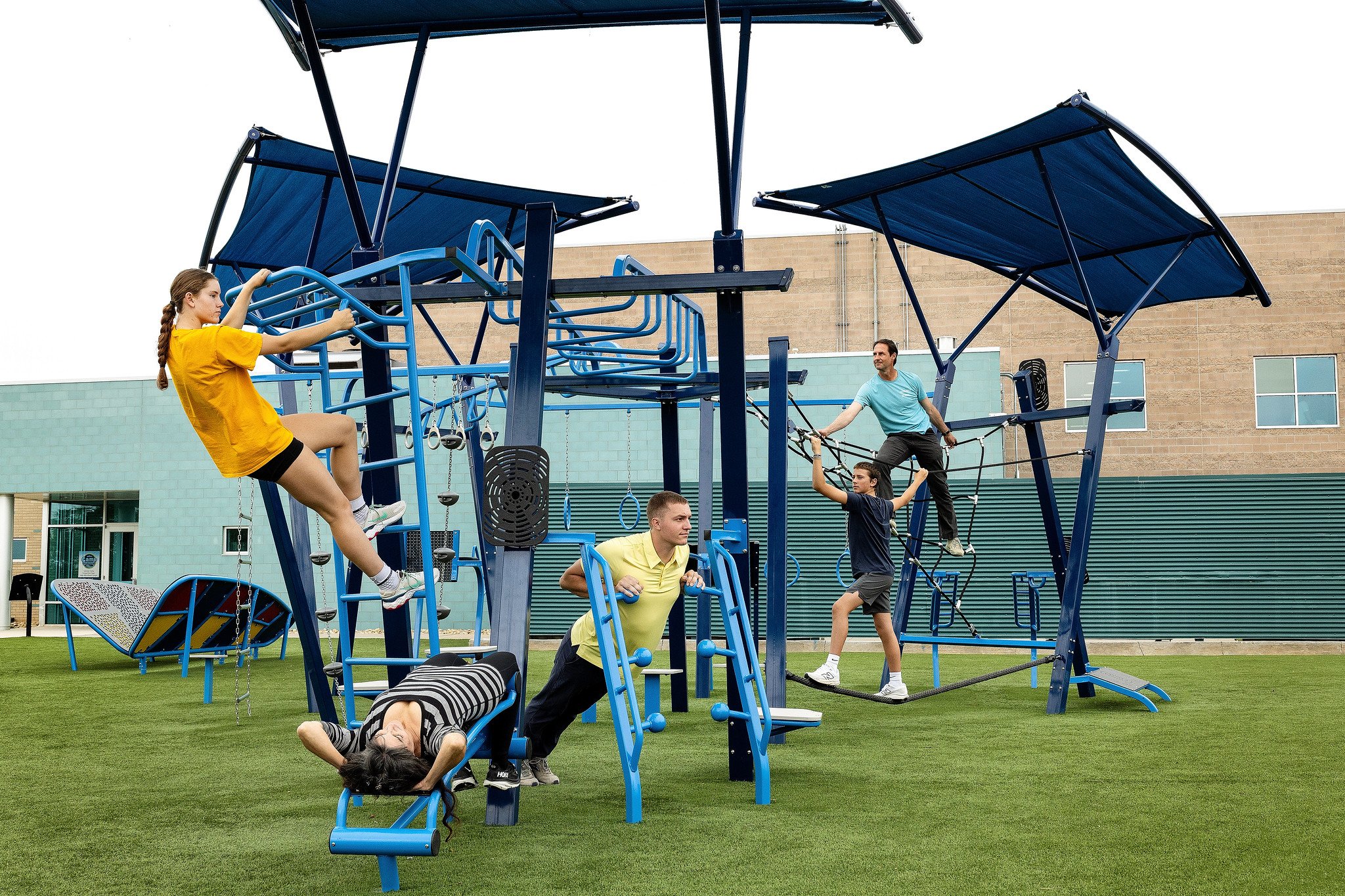 Adults working out on outdoor fitness equipment outside community center