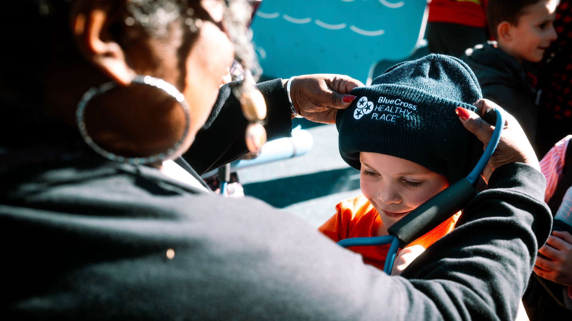 BCBS Healthy Place Grand Opening - woman putting BCBS hat on kid's head