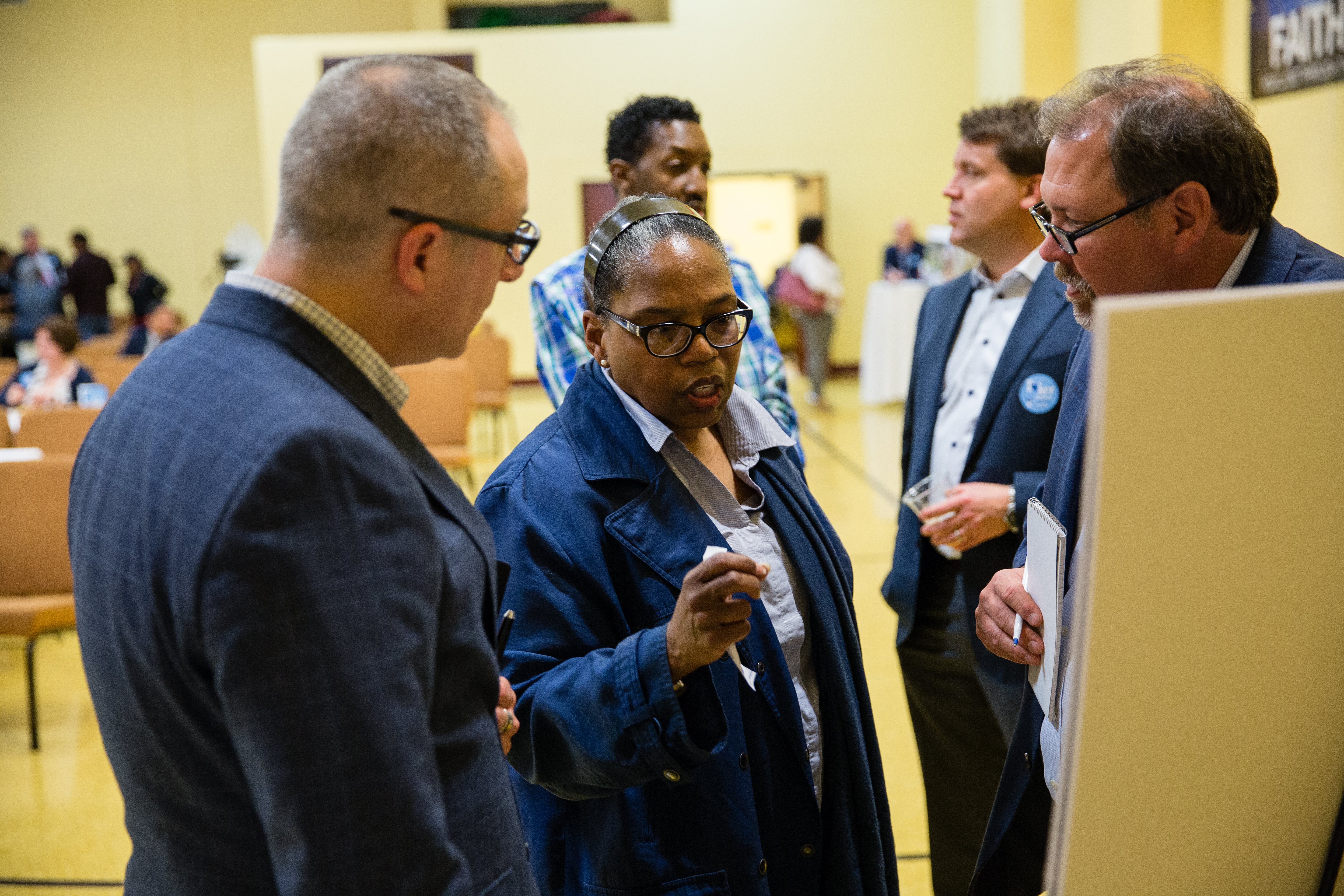 Group of adults in discussion while looking at a board together.