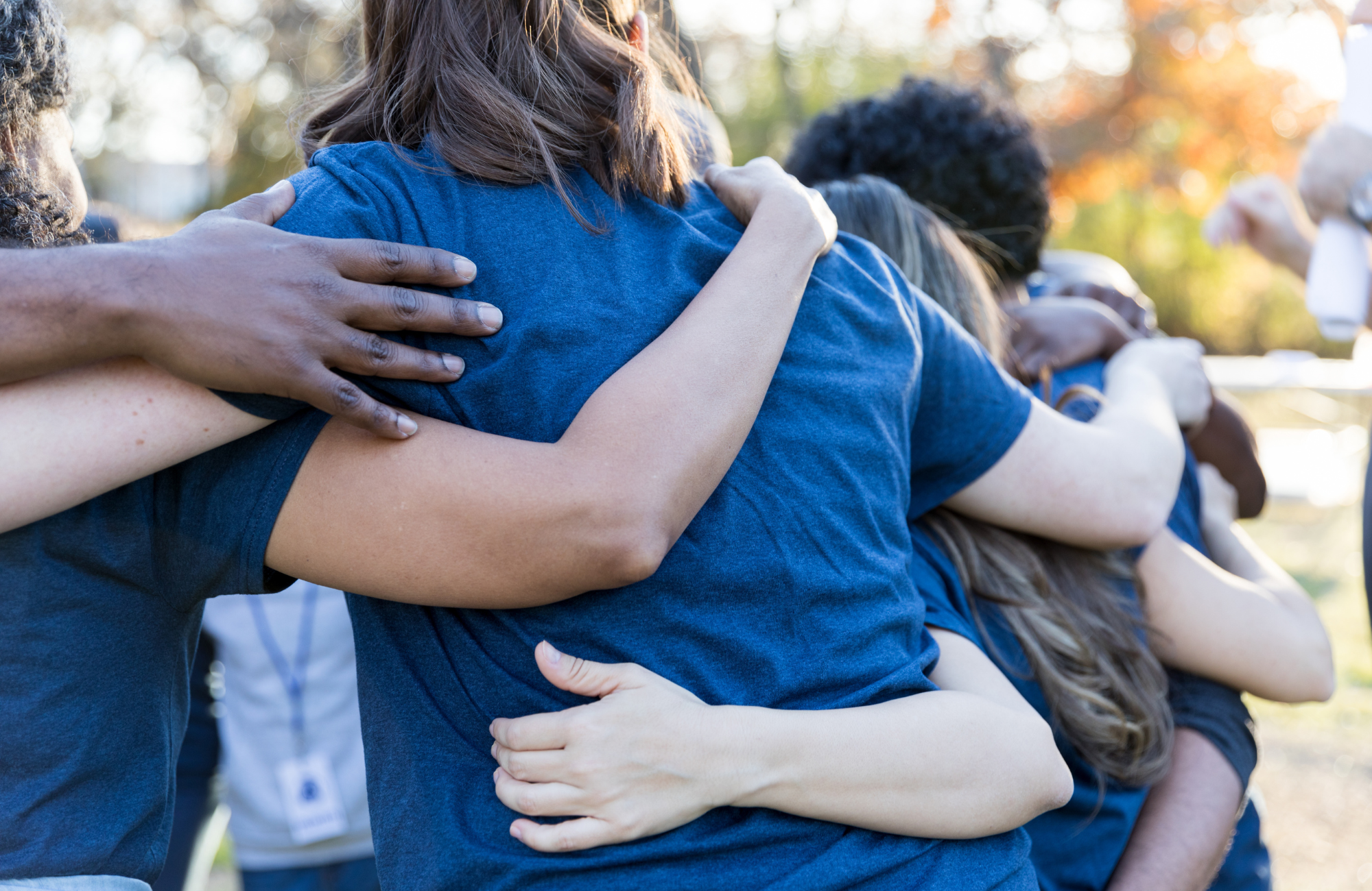 Group of volunteers with arms around each other outdoors