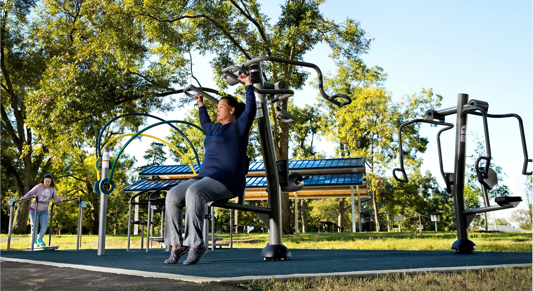 Woman using arm press IP outdoor fitness equipment