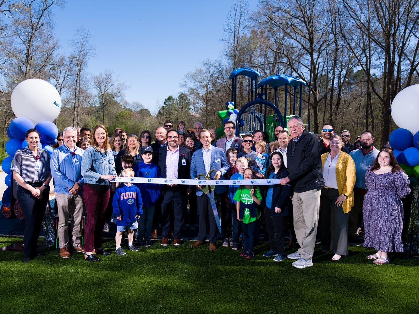 Group photo of ribbon cutting with multiple men, women and children smiling 