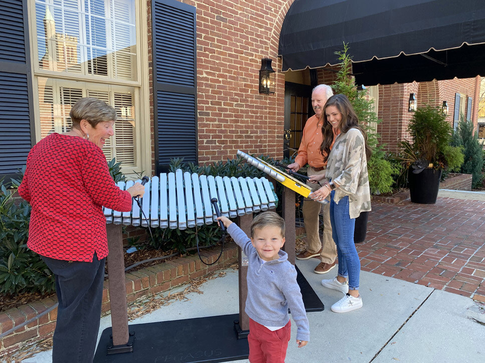 Family playing with xylophone outside building