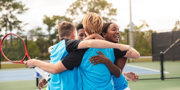 Kids hugging on tennis court