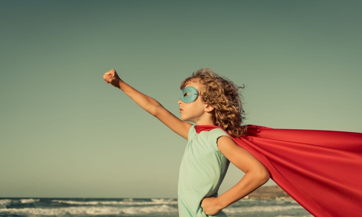 a heroic child with an outstretched arm wearing a mask and cape