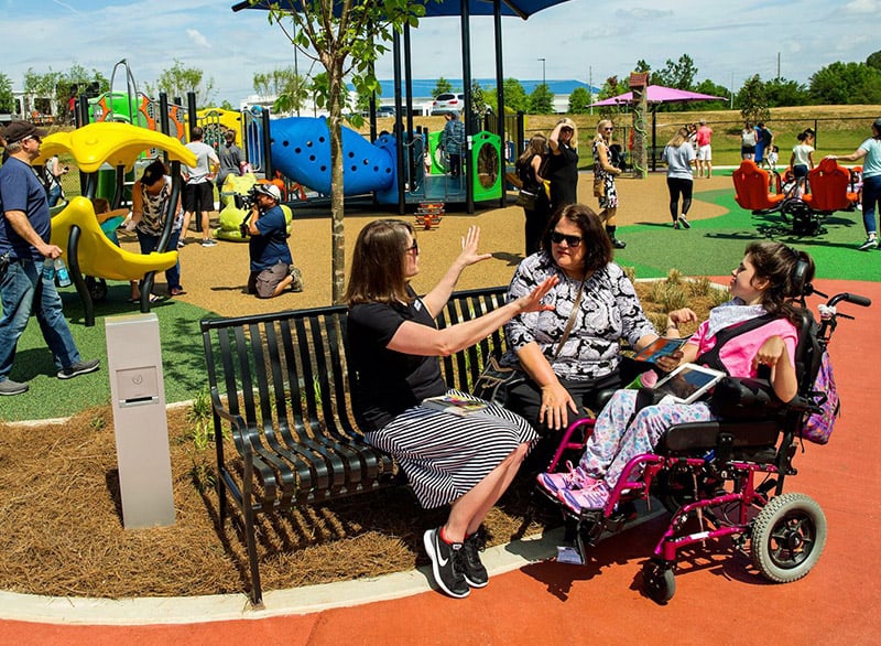 Family sitting at an IMPACT Parks playground bench