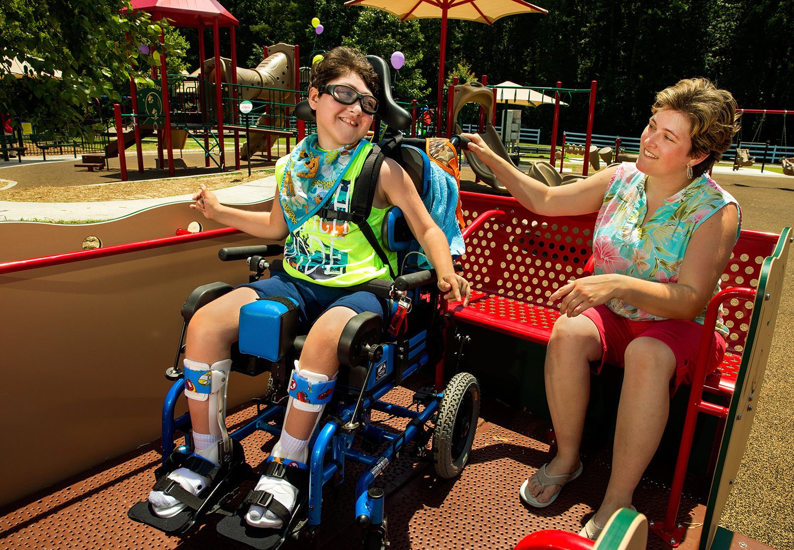 Mother and son in wheelchair on inclusive play equipment in Trillium